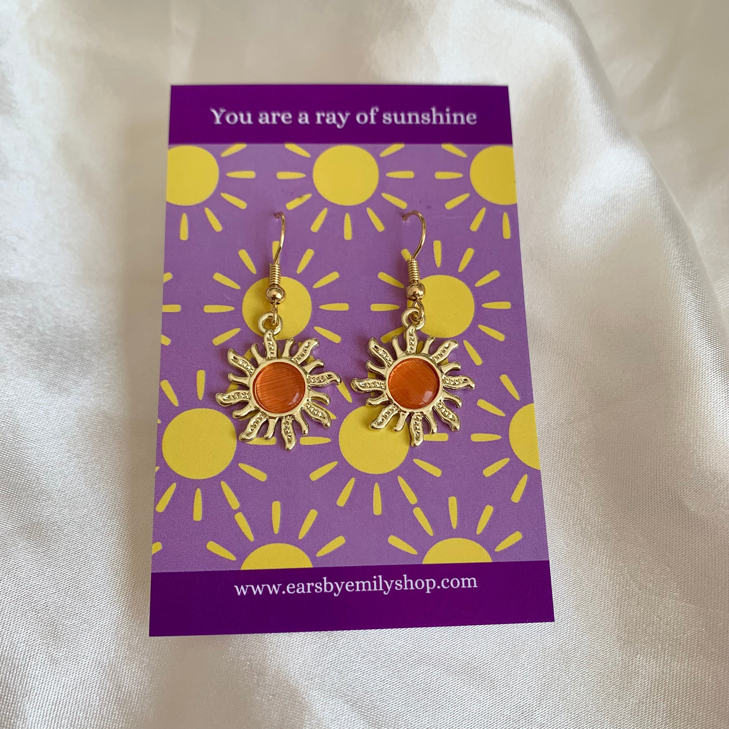 Gold and orange dangle earrings in gift bag on sunshine card
